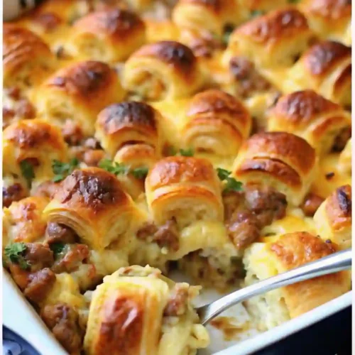Golden-brown sausage croissant breakfast casserole baked in a dish, filled with melted cheese and flaky croissant pieces.