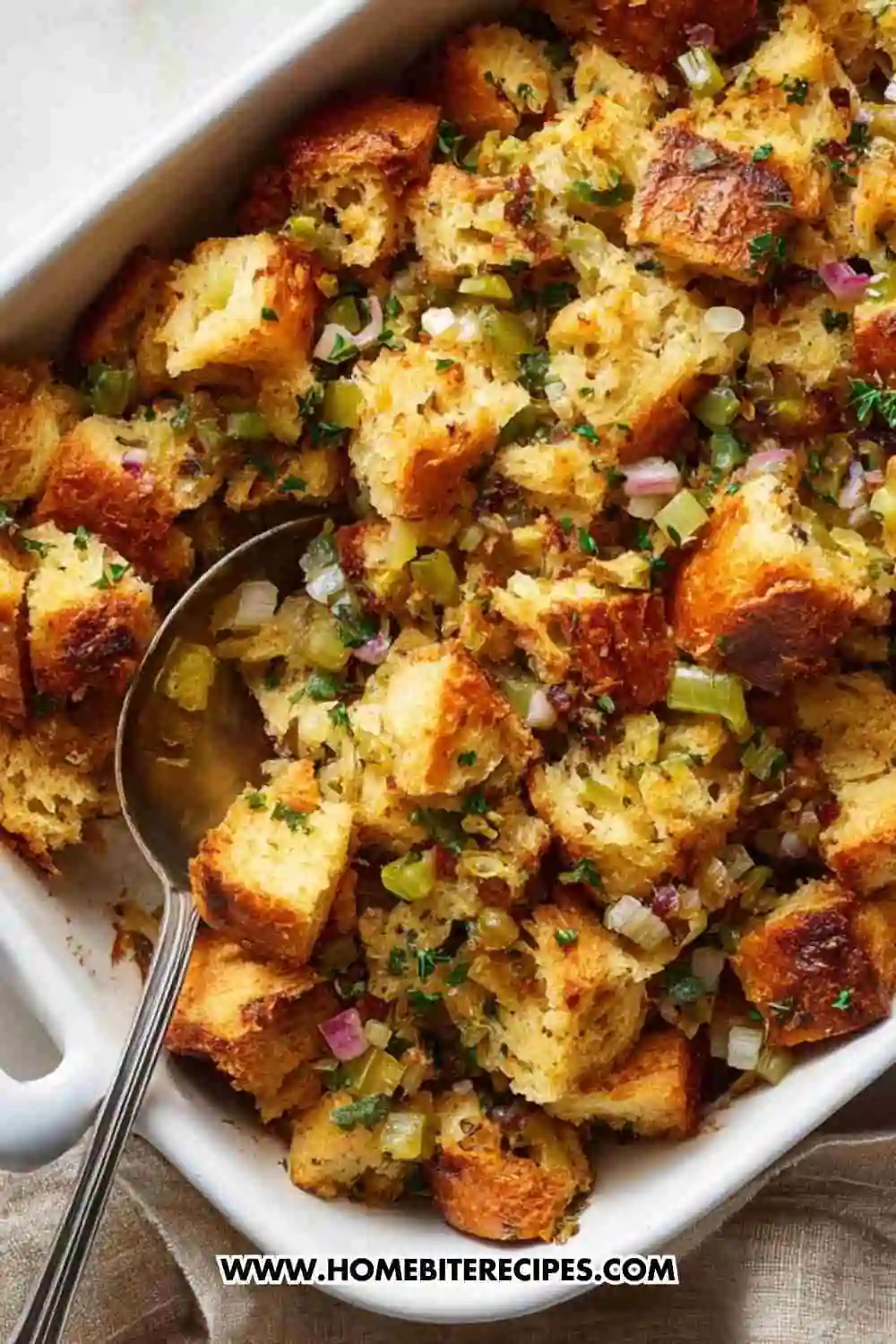 Classic Thanksgiving stuffing made with golden toasted bread cubes, celery, onions, and fresh herbs in a white baking dish.
