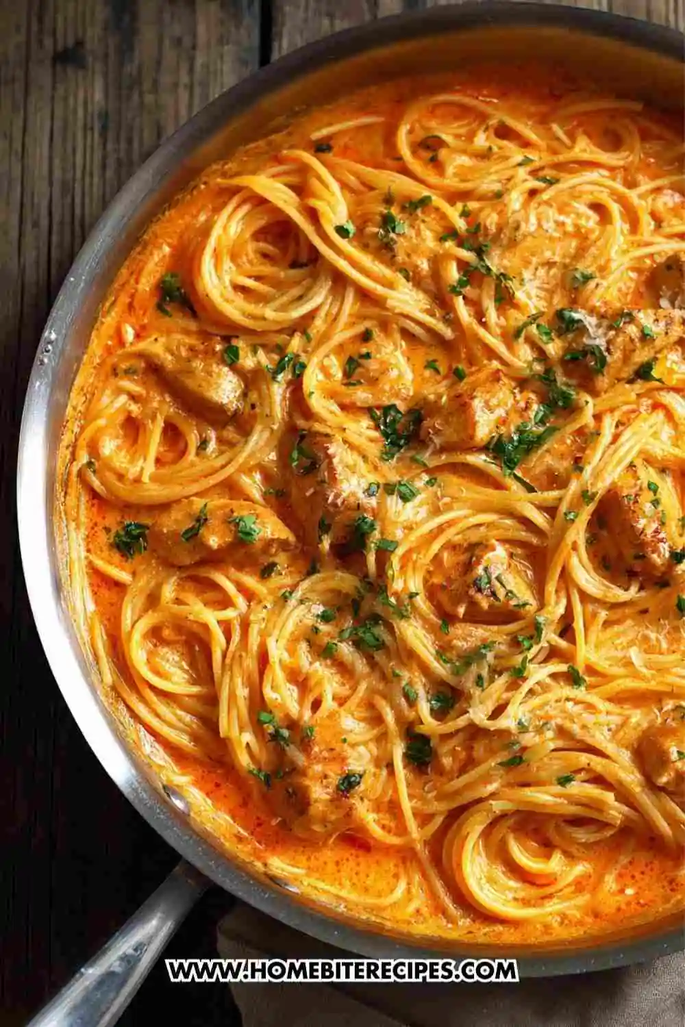 creamy garlic chicken pasta coated in a rich tomato-cream sauce, garnished with fresh parsley.