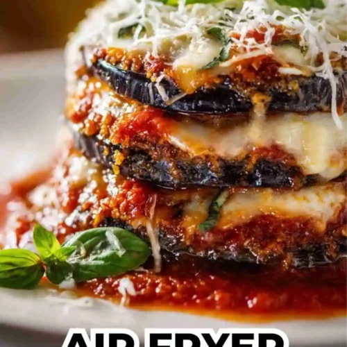 Golden, crispy air fryer eggplant parmesan layered with marinara sauce, melted mozzarella, and fresh basil on a white plate.