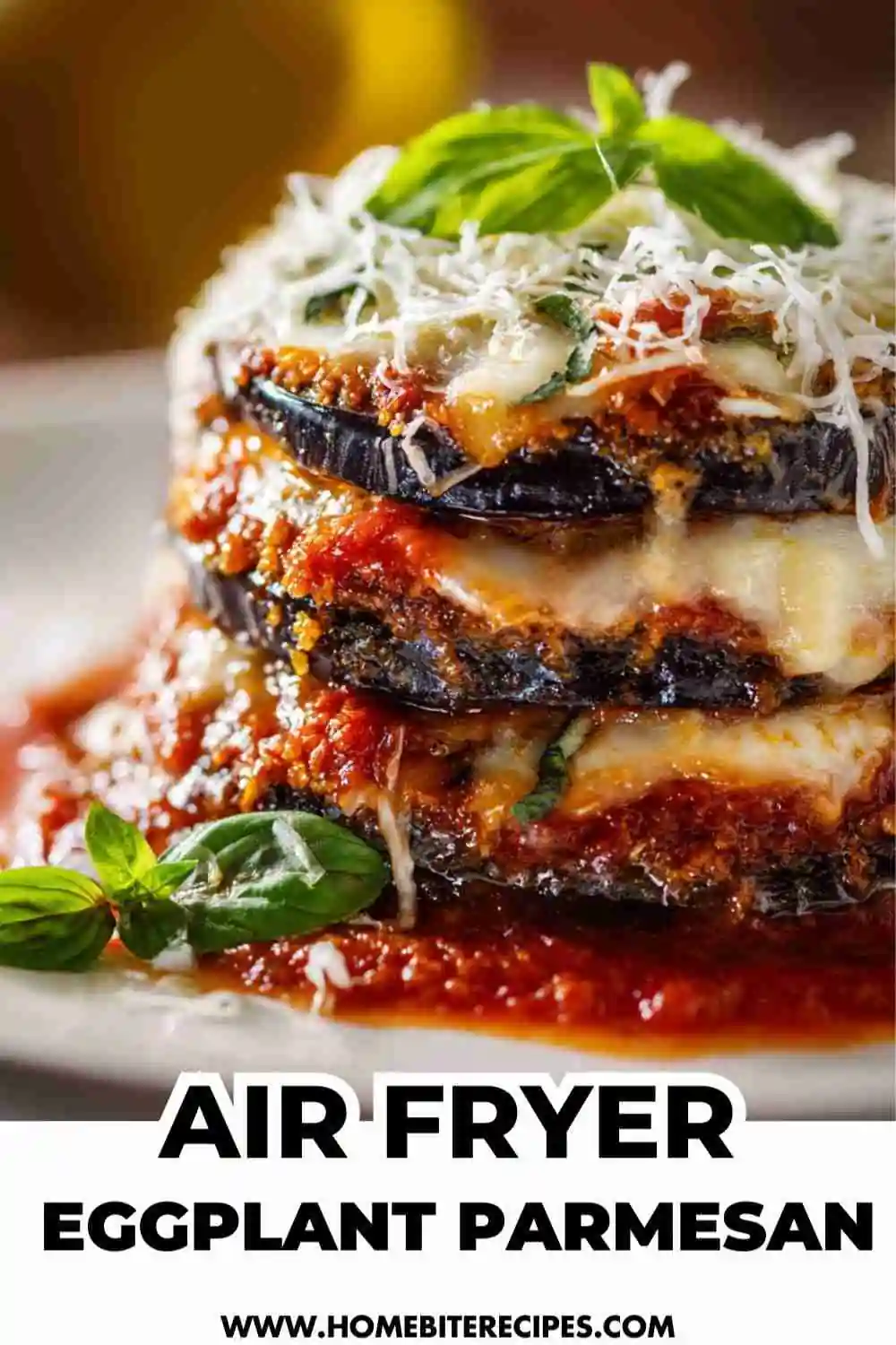 Golden, crispy air fryer eggplant parmesan layered with marinara sauce, melted mozzarella, and fresh basil on a white plate.