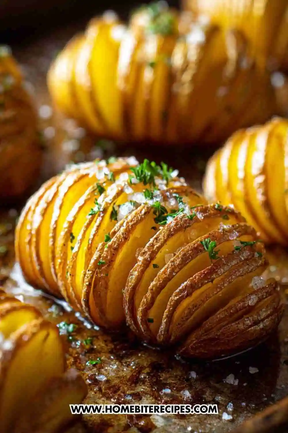 Golden brown air fryer Hasselback potatoes topped with garlic butter, herbs, and sea salt on a baking tray.