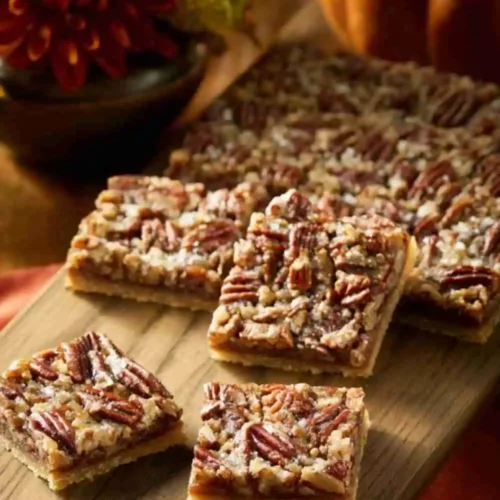 Easy Pecan Pie Bars with a golden crust and caramelized pecan topping, served on a wooden board.
