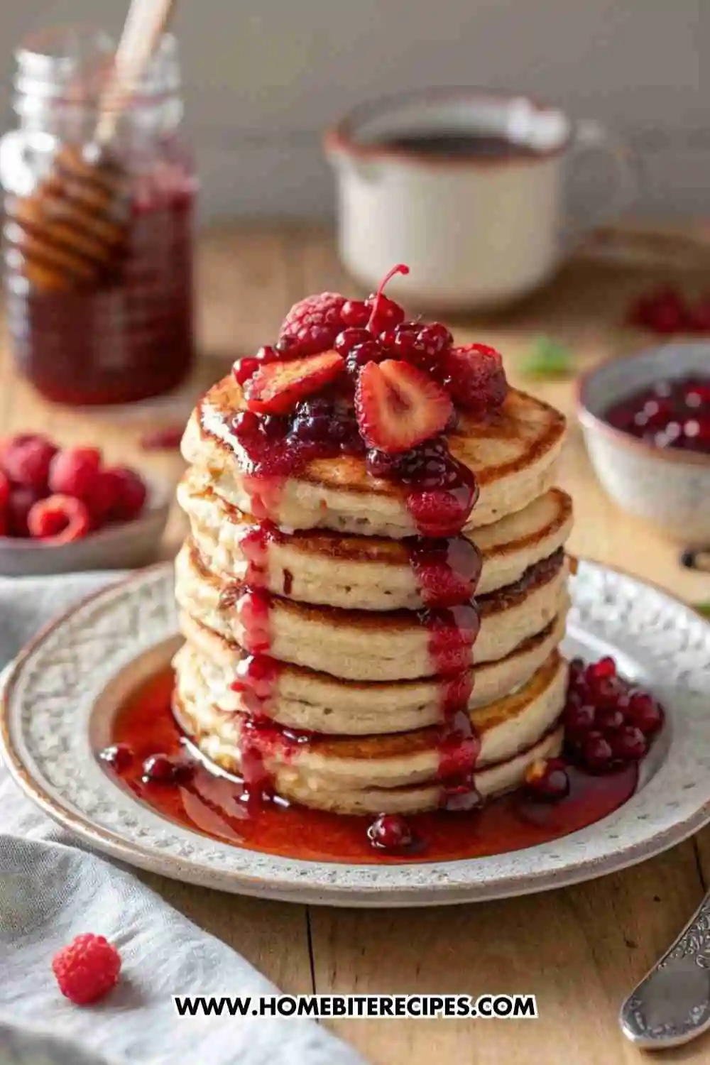 A tall stack of fluffy gluten-free pancakes topped with homemade berry compote made of strawberries, raspberries, and currants.