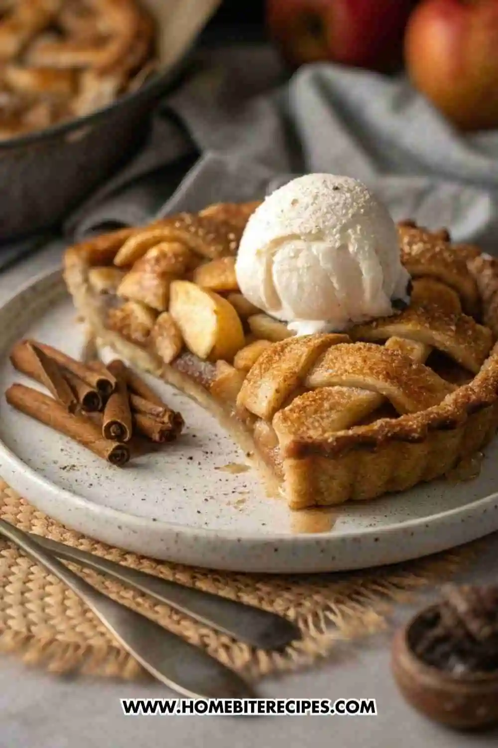 A slice of gluten-free apple pie topped with a scoop of vanilla ice cream, garnished with cinnamon sticks, on a rustic plate and cozy fall setting.
