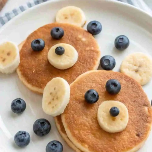 Cute bear face pancakes made with gluten-free batter, decorated with banana slices and blueberries for a fun kids’ breakfast.
