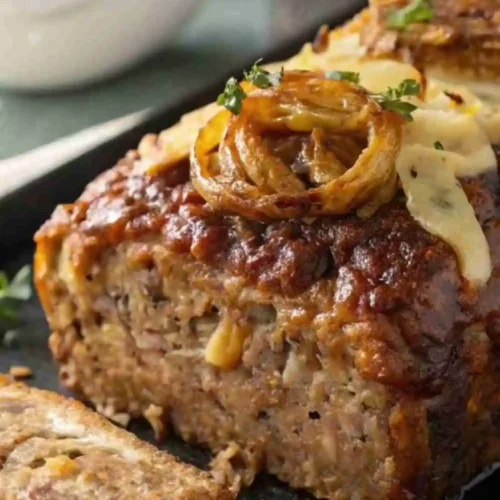 Classic homemade meatloaf topped with caramelized onions and fresh herbs, sliced and ready to serve.