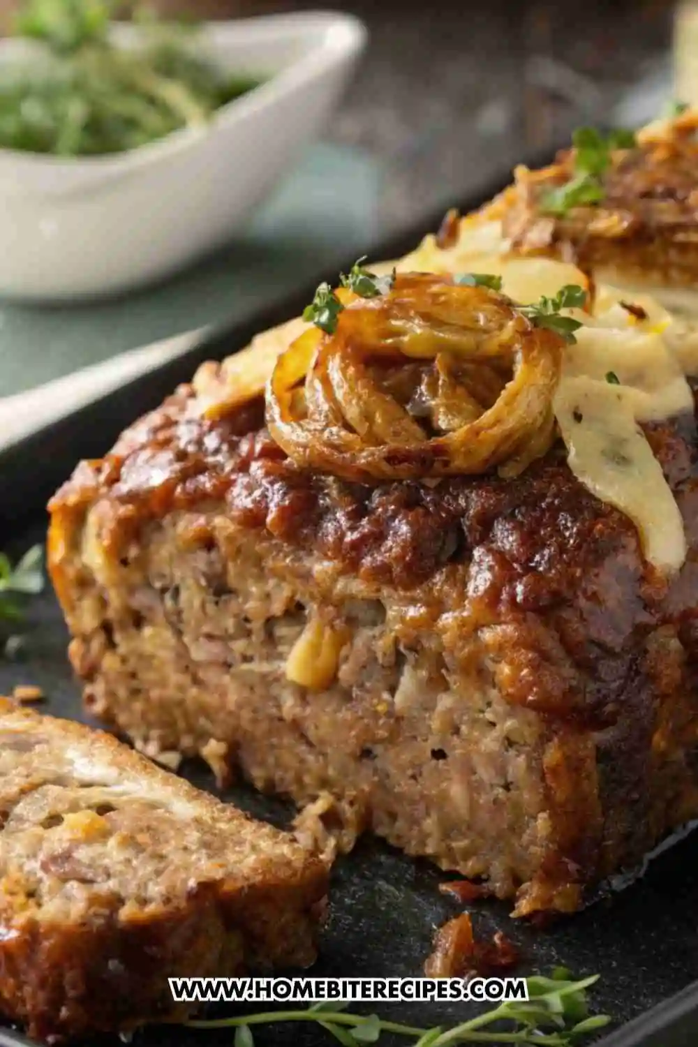Classic homemade meatloaf topped with caramelized onions and fresh herbs, sliced and ready to serve.