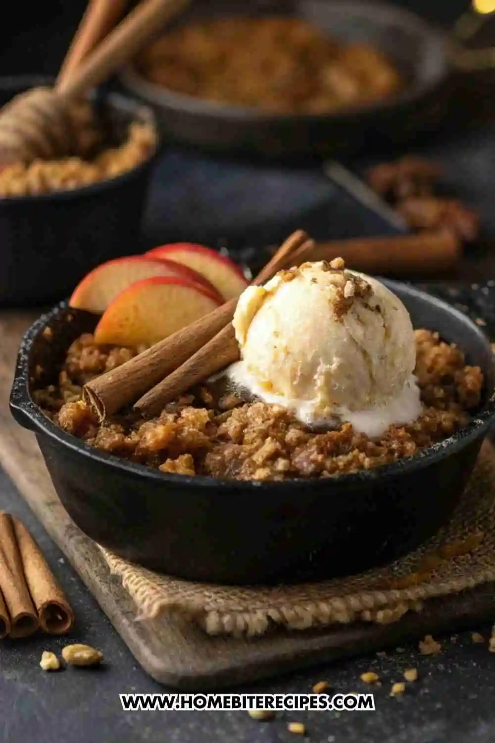 Warm skillet apple crisp topped with vanilla ice cream and cinnamon sticks, served in a cast iron pan.