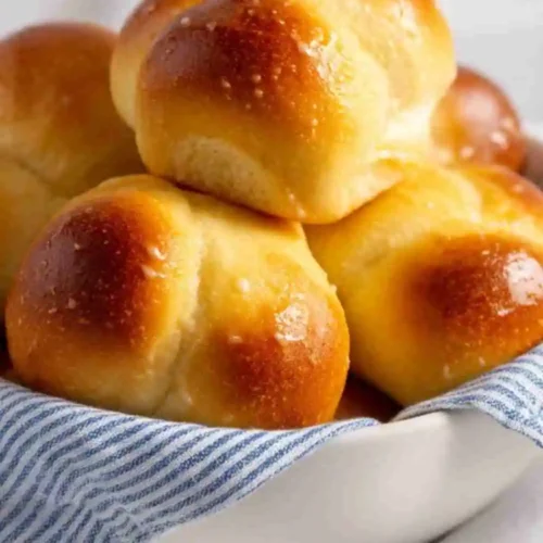 Soft and fluffy homemade dinner rolls with a golden brown crust served in a bowl.