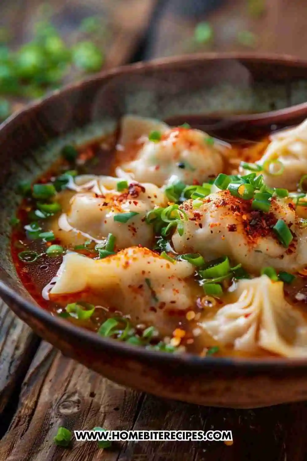 A bowl of spicy dumpling soup with chili oil broth, green onions, and tender dumplings served hot and steaming.