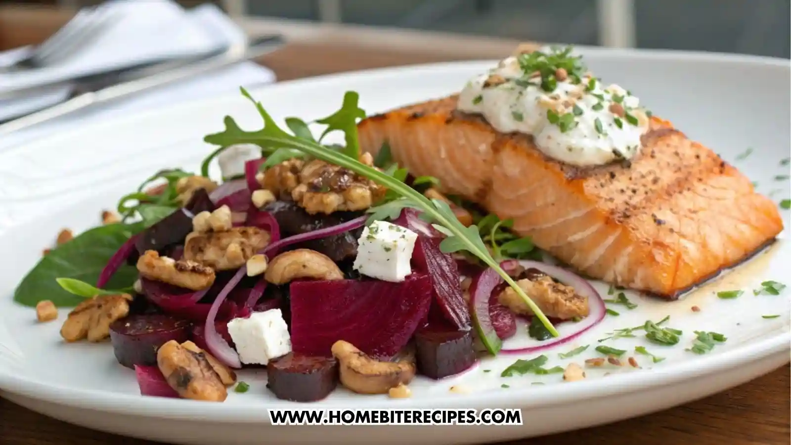 Close-up of a beetroot salad with roasted beet cubes, feta cheese, walnuts, red onion slices, herbs, and olive oil served with grilled salmon on a white plate.