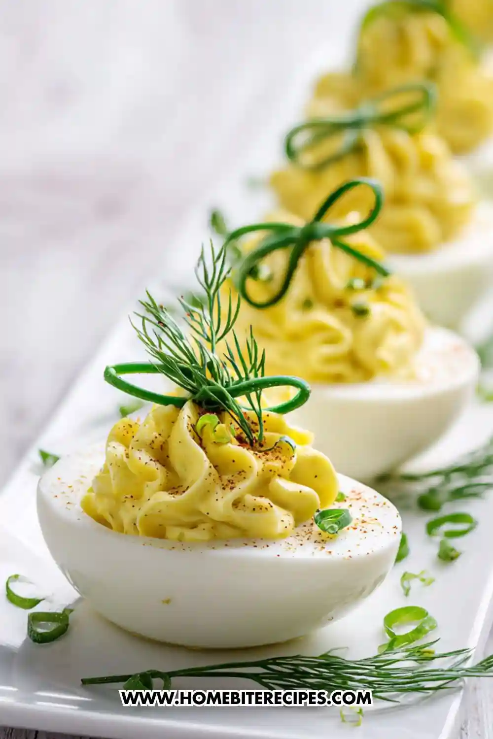 Close-up of elegant deviled eggs topped with creamy yolk filling, paprika, and fresh dill garnish, arranged on a white platter.