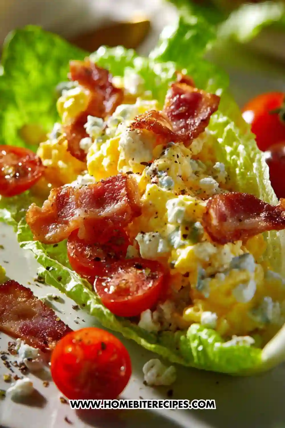 Close-up of scrambled egg lettuce cups topped with crispy beef strips, cherry tomatoes, and crumbled cheese on fresh romaine leaves.