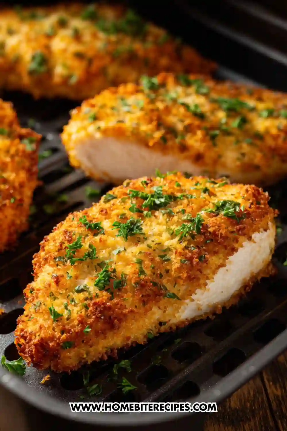 Golden and crispy air fryer chicken breasts topped with chopped parsley, served fresh from the air fryer basket.