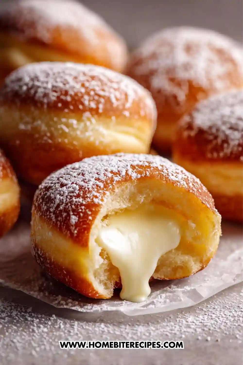 Fresh cream-filled donuts dusted with powdered sugar, one donut broken open showing creamy vanilla filling oozing out
