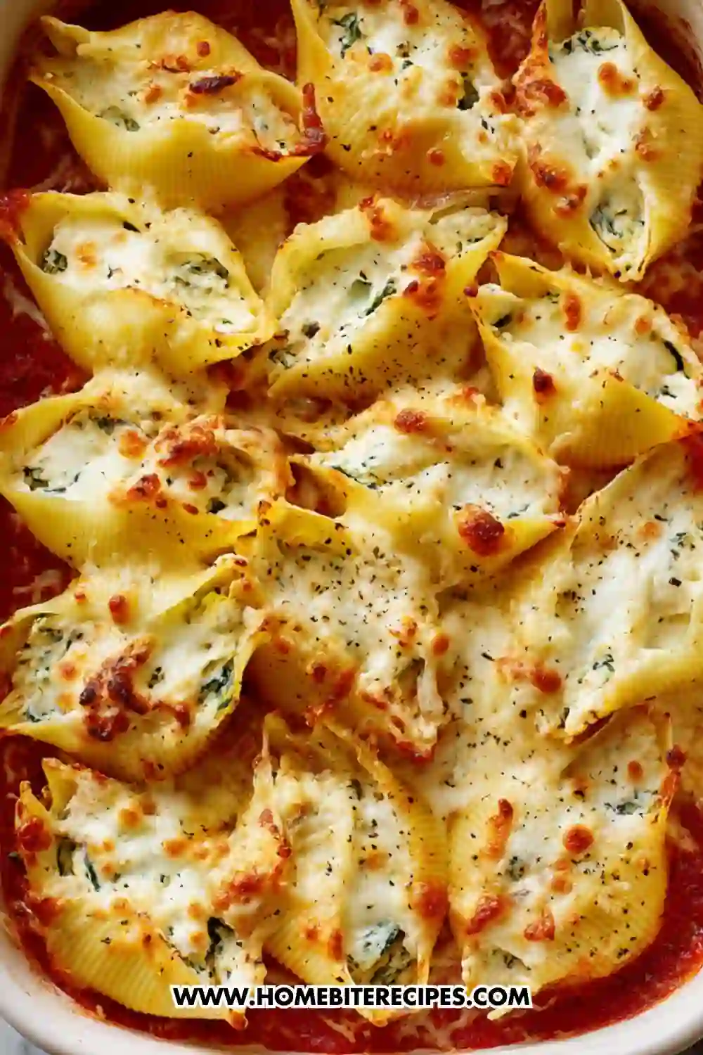 Close-up of baked jumbo pasta shells stuffed with creamy ricotta and spinach, topped with melted golden cheese and served over marinara sauce