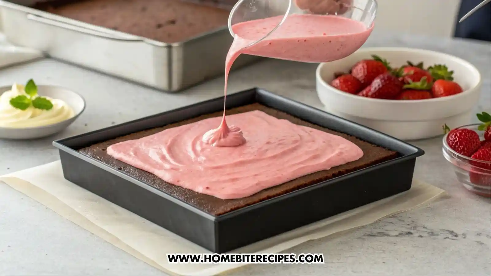 a square dessert mold filled with a layer of chocolate cake and a hand carefully pouring pink strawberry mousse over the cake base
