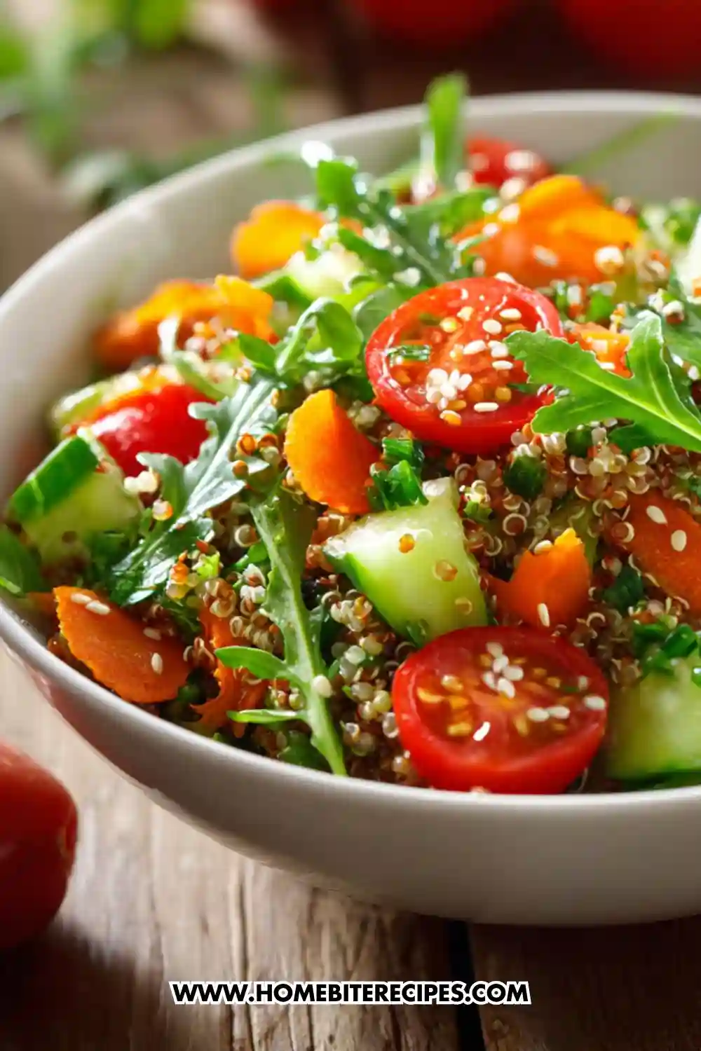 Colorful quinoa salad with cherry tomatoes, cucumber, arugula, carrots, and sesame seeds served in a white bowl — a perfect everyday healthy lunch option.