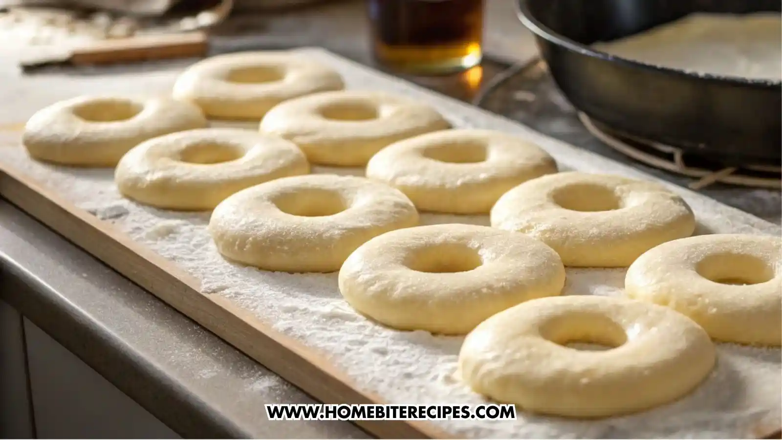 Risen donut dough cut into several full circles, visibly puffed and airy after resting, arranged on a lightly floured surface.