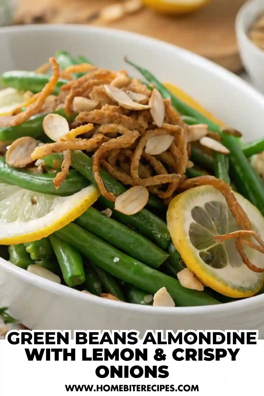 Fresh green beans tossed with toasted almonds and lemon slices, topped with crispy fried onions, served in a white dish.
