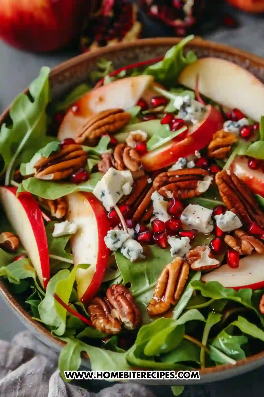 Healthy apple and pomegranate salad with blue cheese, pecans, and leafy greens – a colorful immunity-boosting meal full of vitamins and antioxidants.