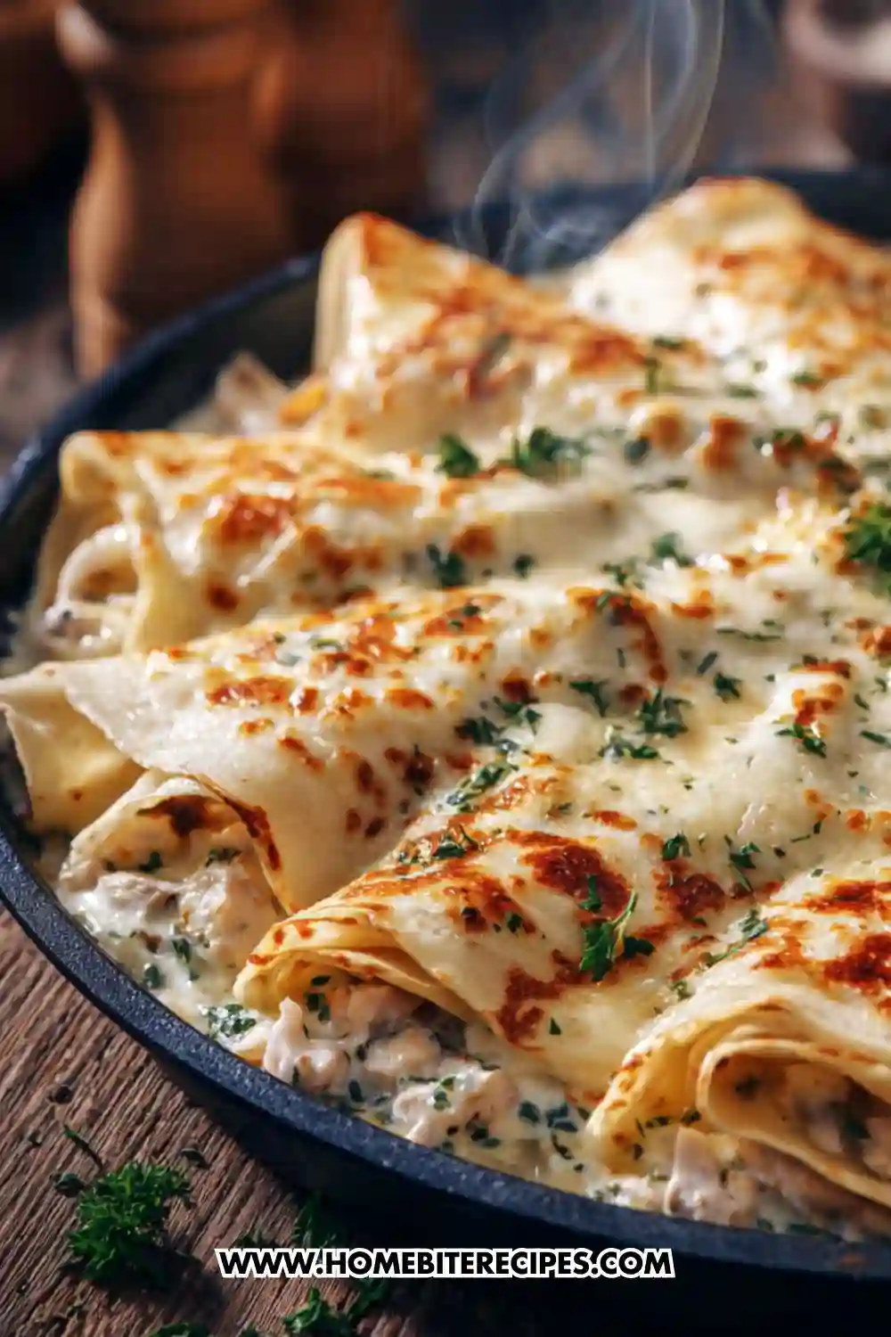 Savory crêpe casserole filled with shredded chicken, mushrooms, and creamy béchamel sauce, topped with melted golden cheese inside a steaming skillet