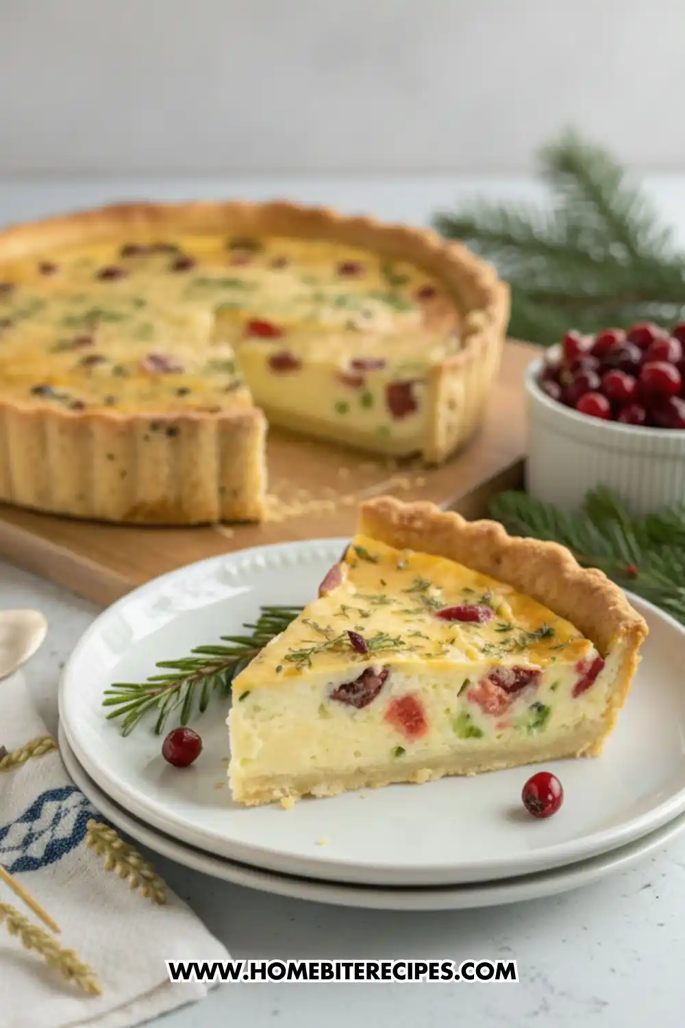 Slice of holiday quiche with cranberries, vegetables, creamy filling, and a buttery crust on a white plate with fresh rosemary and cranberries