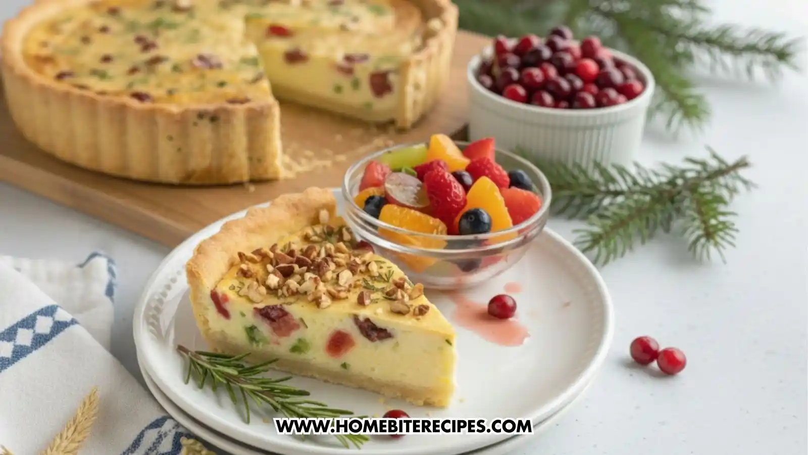 Slice of Holiday Cranberry & Veggie Quiche, creamy filling, and a buttery crust on a white plate with fresh rosemary and cranberries served with fruit salad bowl