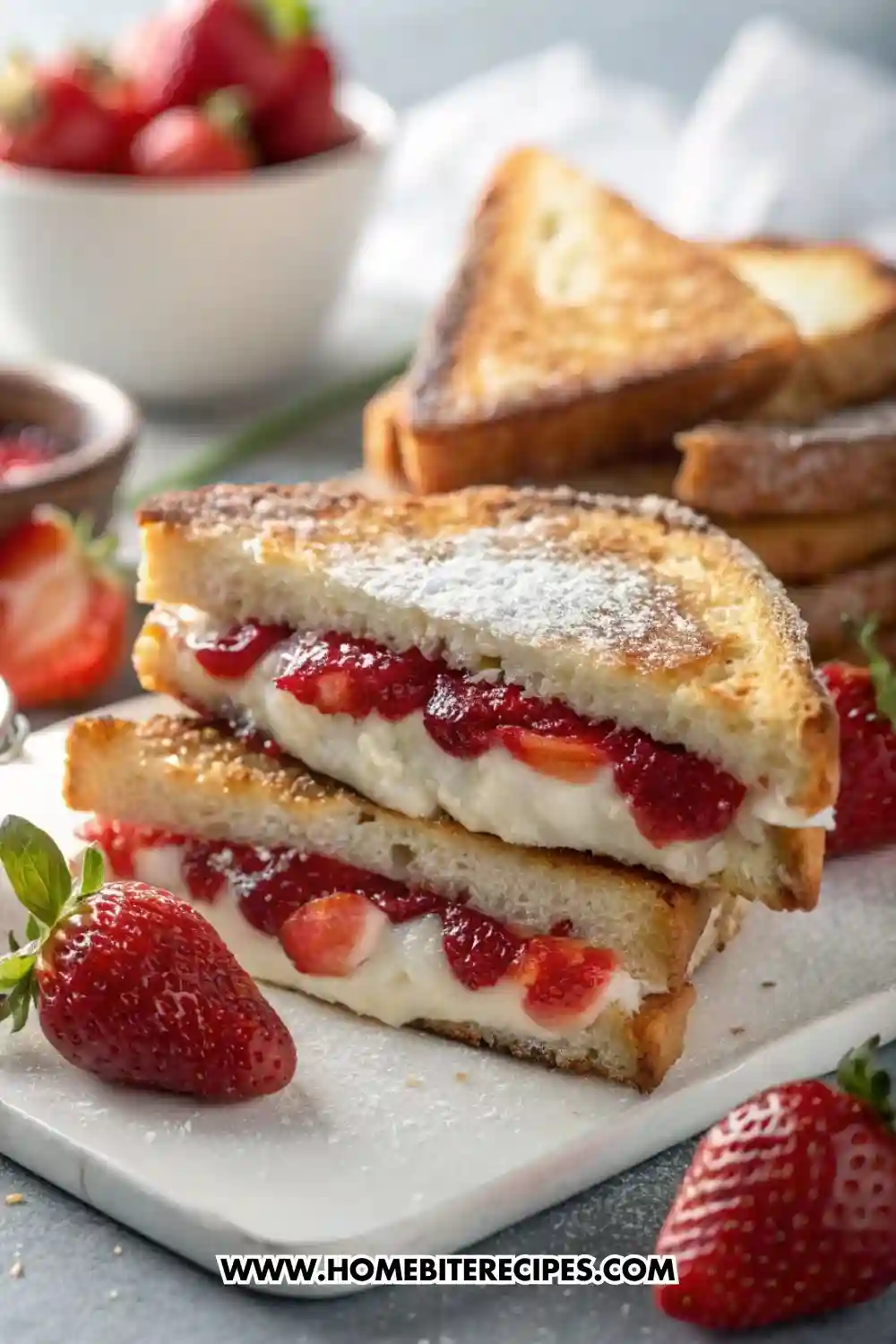Close-up of golden toasted French toast stuffed with creamy filling and fresh strawberry compote, sliced in half and dusted with powdered sugar, served with whole strawberries.