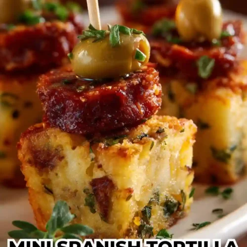 Mini Spanish tortilla bites topped with slices of spicy chorizo and green olives on skewers, garnished with herbs — a bite-sized Spanish tapas appetizer.