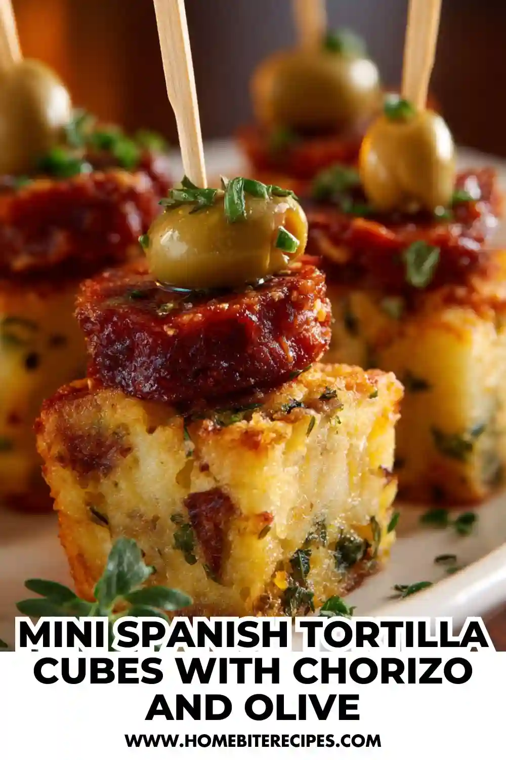 Mini Spanish tortilla bites topped with slices of spicy chorizo and green olives on skewers, garnished with herbs — a bite-sized Spanish tapas appetizer.