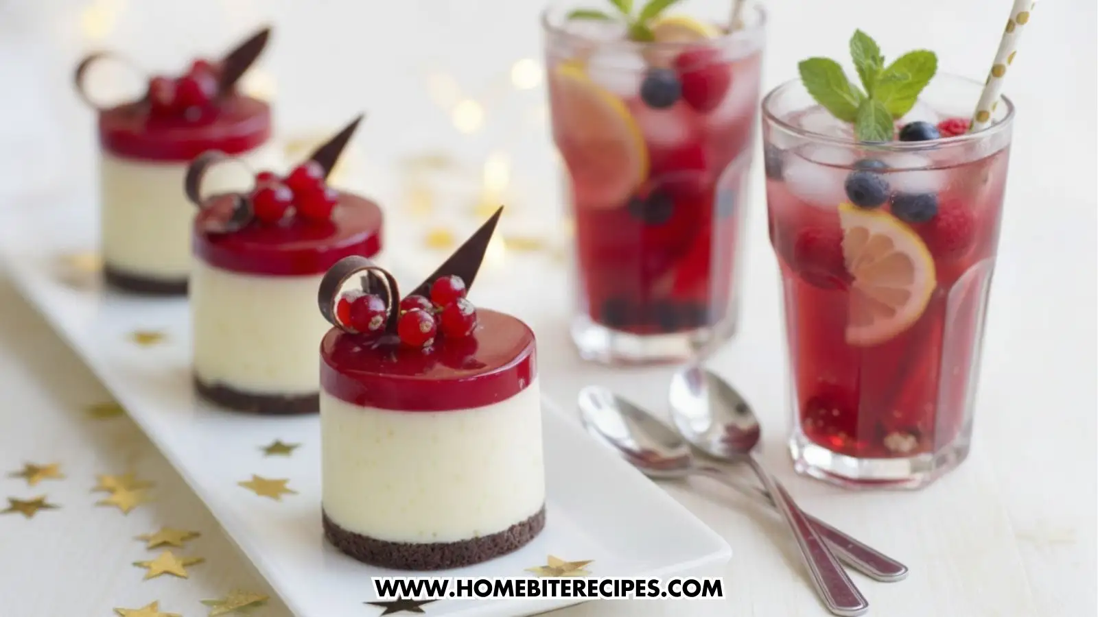 Mini white chocolate mousse cakes with red berry glaze and chocolate decorations, served on a white plate with gold stars, served with two berry-infused iced tea