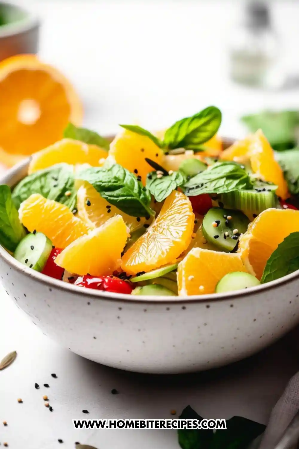 A vibrant bowl of citrus cucumber salad featuring juicy orange slices, fresh mint leaves, cherry tomatoes, and sliced cucumbers, garnished with sesame seeds and served in a white ceramic bowl.