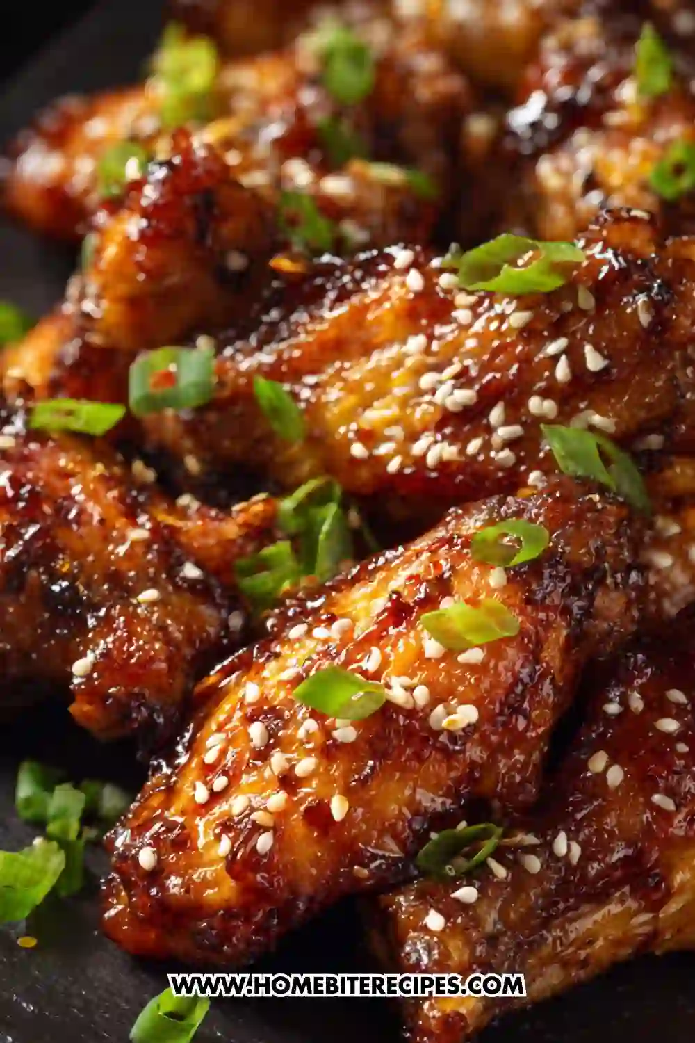 Close-up of sticky honey garlic chicken wings sprinkled with sesame seeds and green onions, perfectly glazed and golden brown.