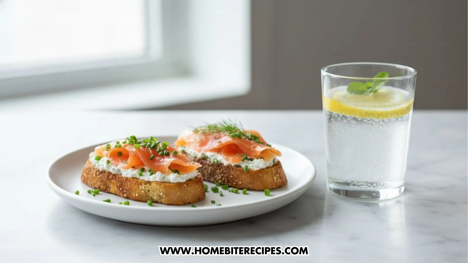 Open-faced crostini topped with creamy herbed cheese, slices of smoked salmon, fresh chives, and dill arranged on a white serving board served with sparkling water with lemon.