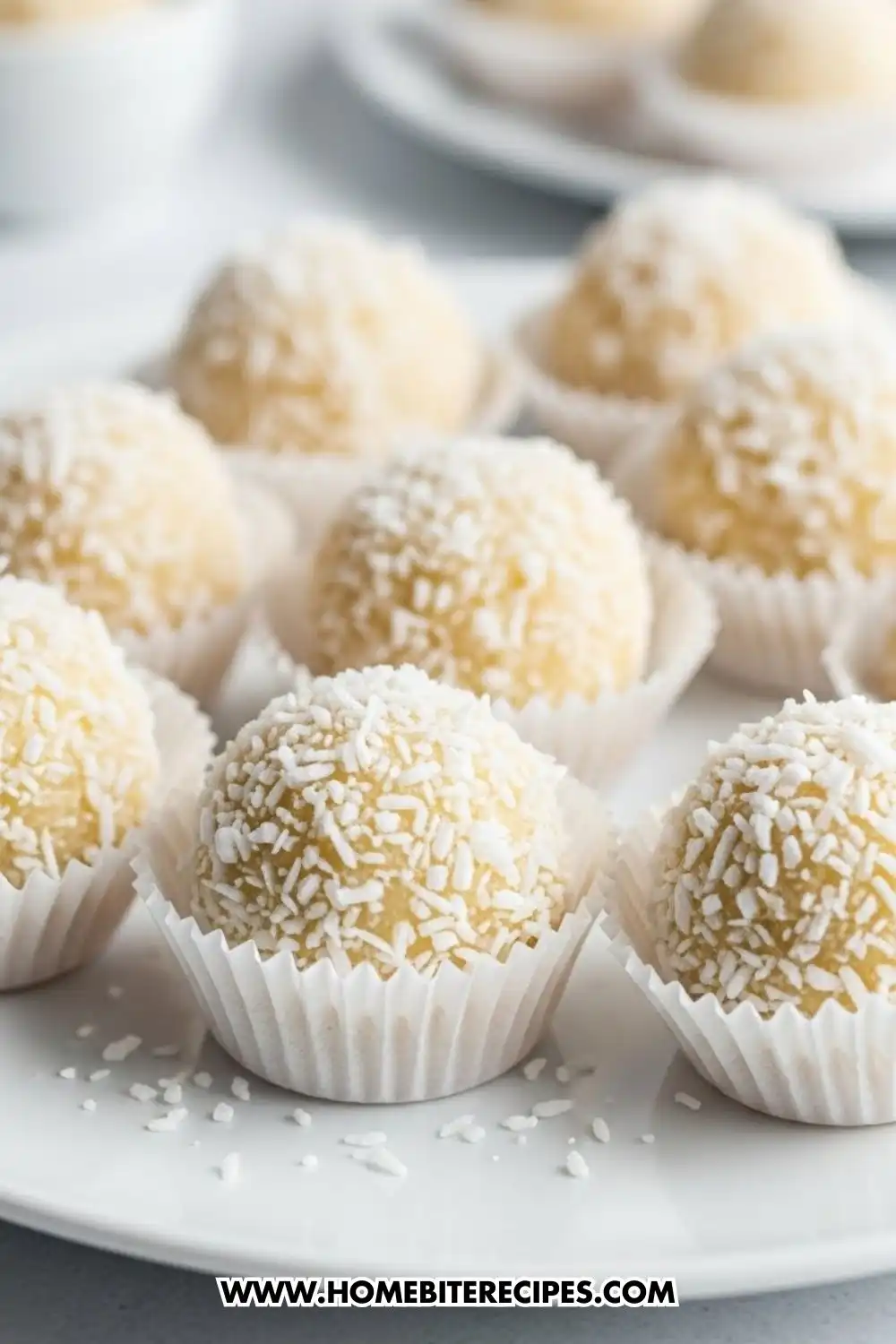 No-bake coconut cookies made with sweetened condensed milk, shaped into white coconut snowball cookies and served in paper liners on a plate.