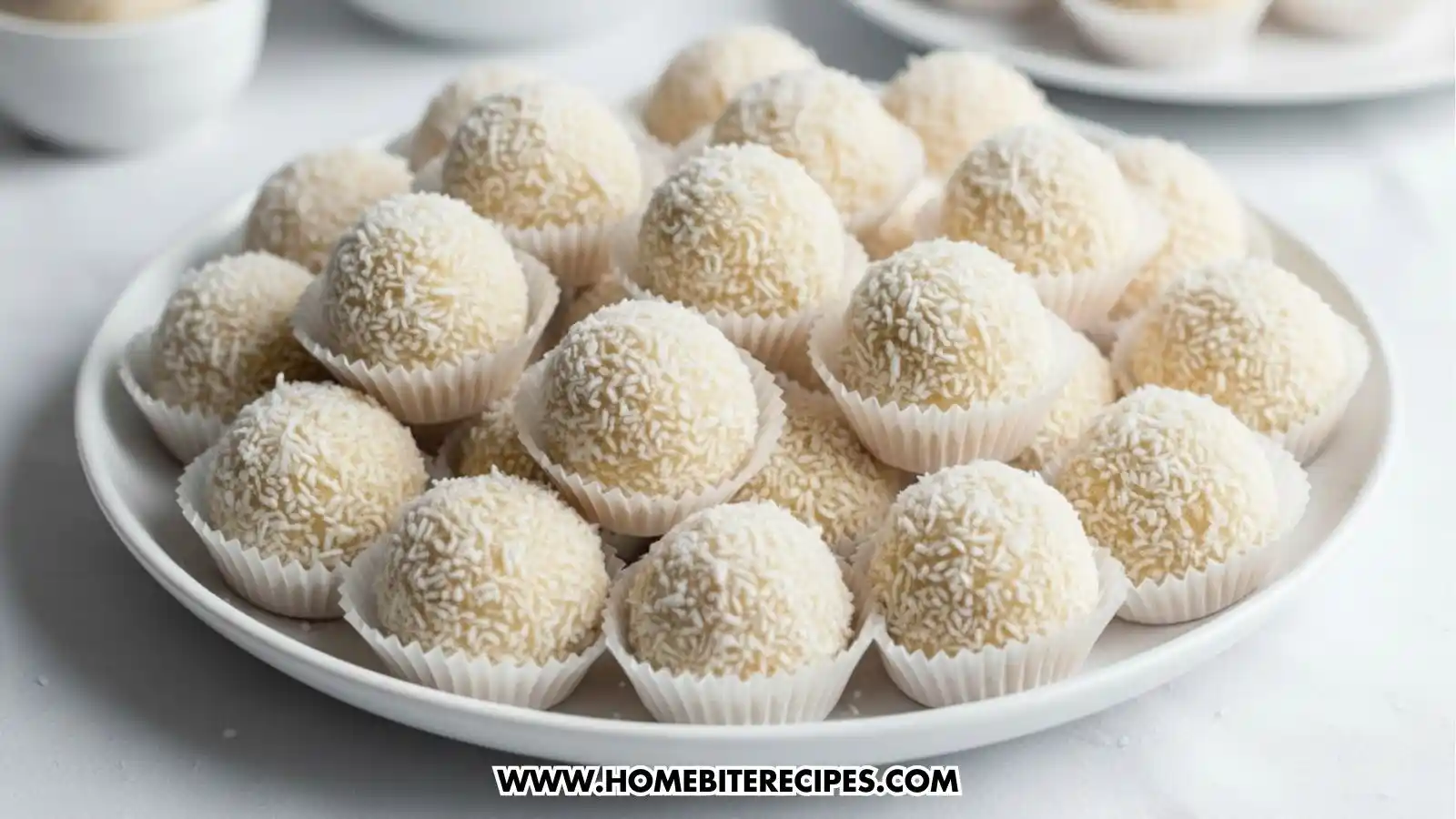 No-bake coconut cookies made with sweetened condensed milk, shaped into white coconut snowball cookies and served in paper liners on a plate.