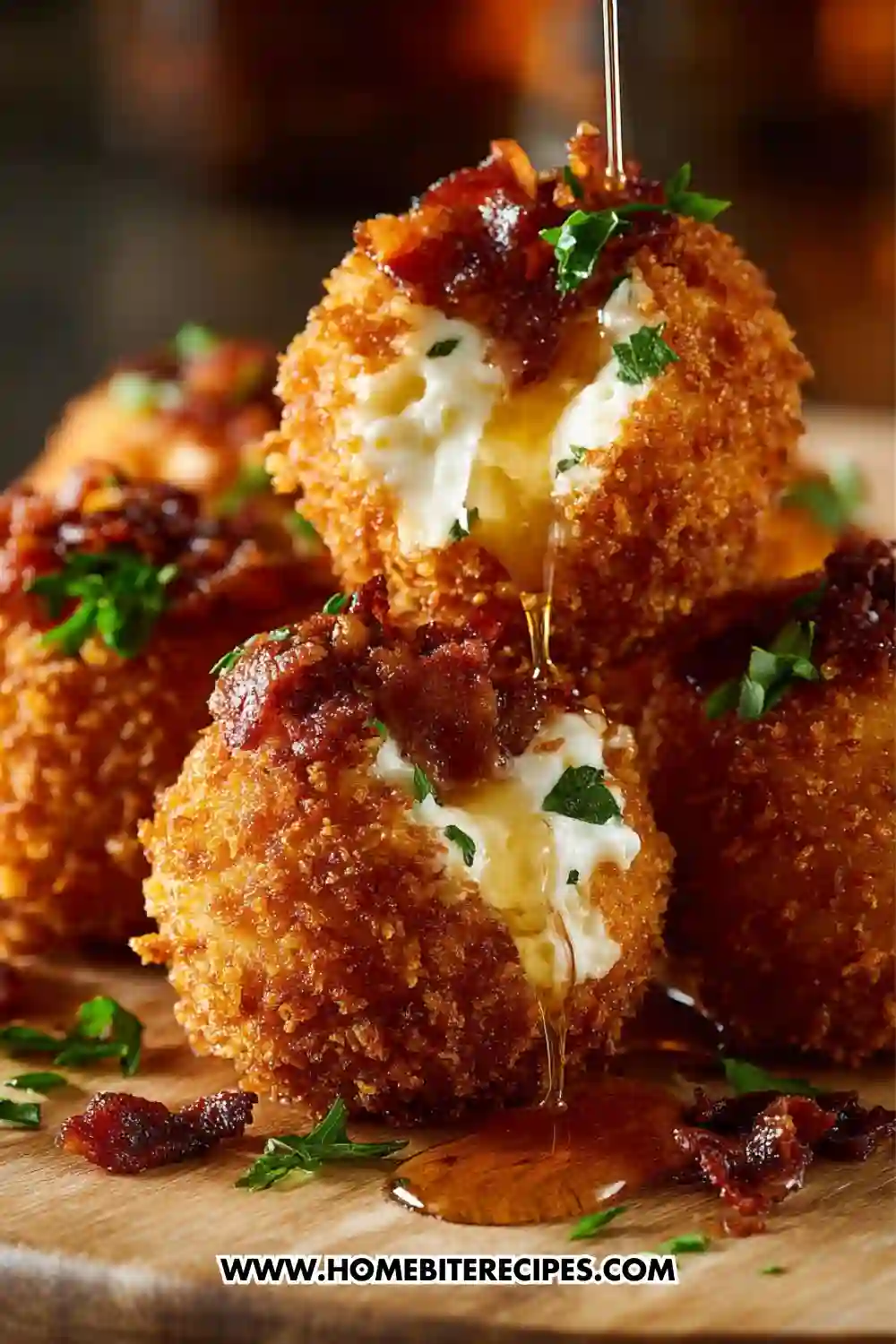 Close-up of crispy buffalo chicken mozzarella bombs filled with melted cheese, topped with bacon and herbs, dripping with sauce.