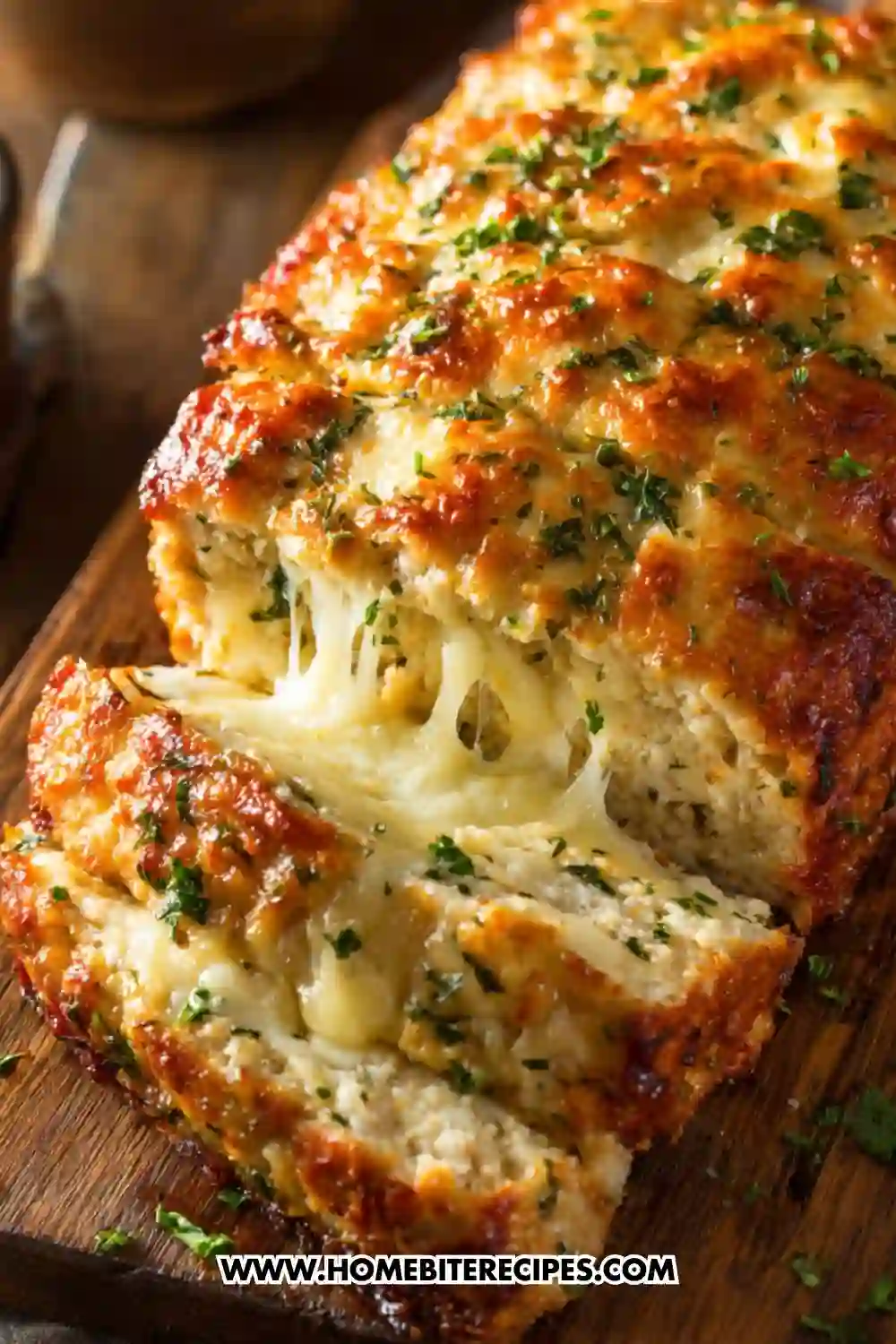 Golden baked cheesy garlic chicken bread loaf with melted cheese stretching between slices, topped with herbs, served on a wooden board.