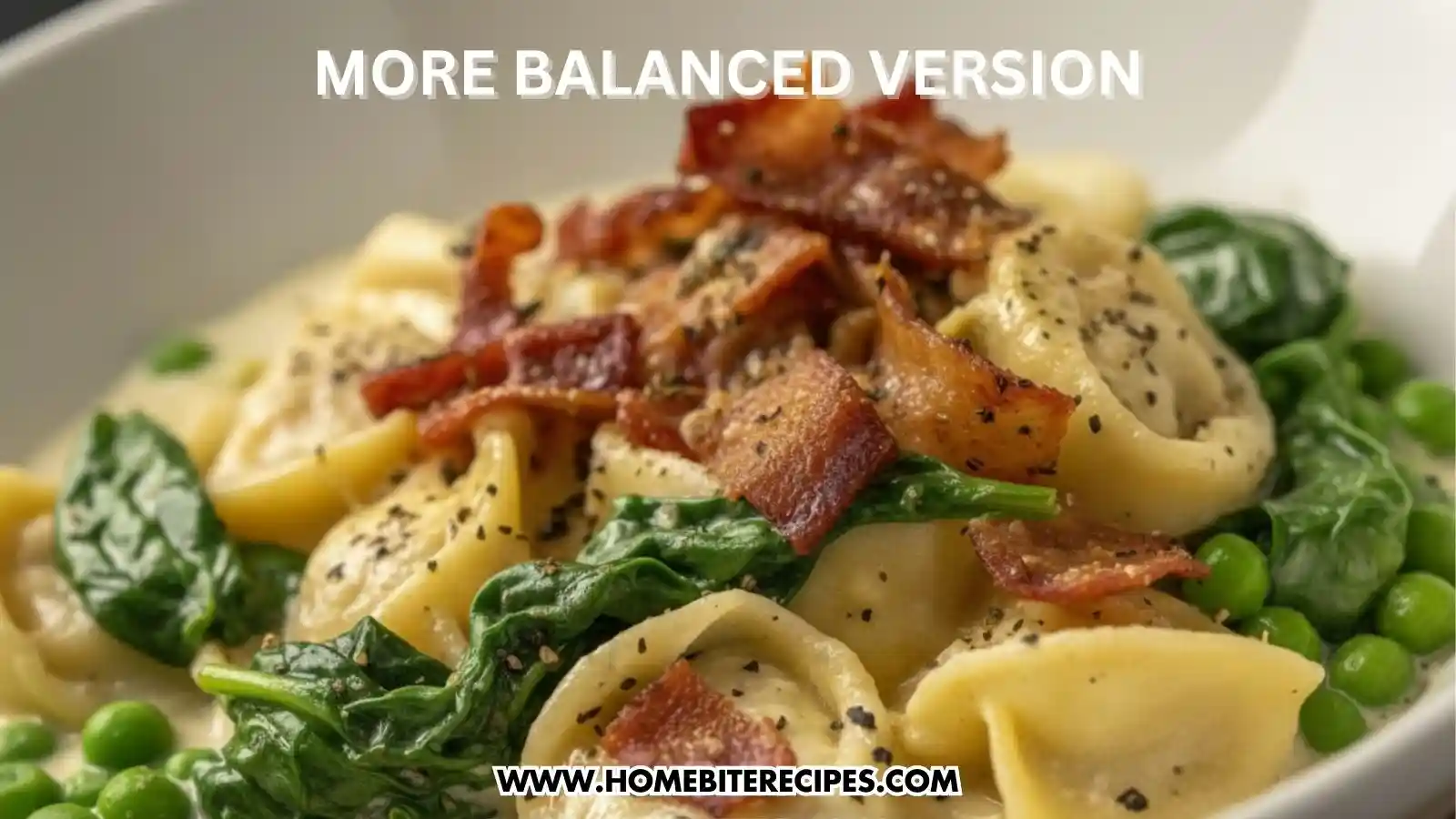 A close-up shot of a "more balanced version" of tortellini Alfredo. The pasta is tossed in a white cream sauce and mixed with bright green peas and wilted spinach leaves. It is garnished with crumbled crispy bacon and cracked black pepper.