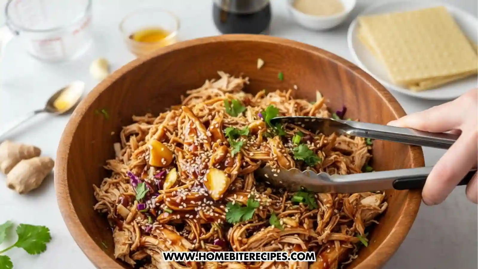 a hand mixing the shredded chicken,with soy sauce, honey, garlic, ginger, and sesame oil to fill the Crispy Asian Chicken Tacos