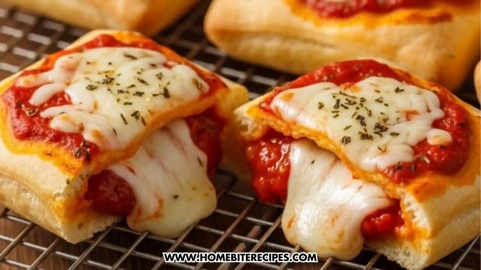 Homemade cheesy pizza pockets baked until golden, filled with melted mozzarella and tomato sauce, resting on a cooling rack with cheese stretching apart.