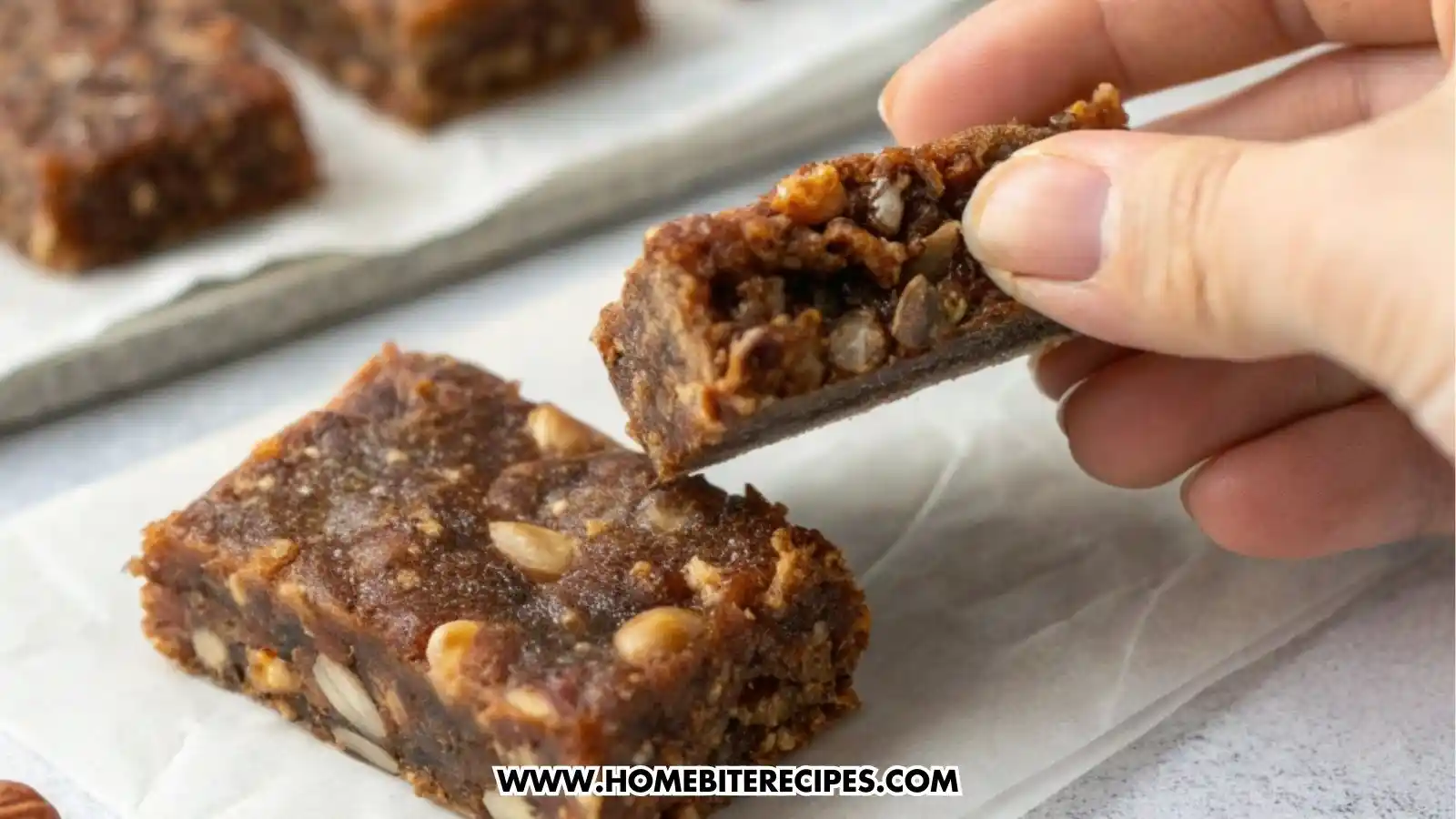 Close-up image of soft, chewy no-bake date bars made with nuts and only five ingredients, displayed on parchment and a serving tray, showcasing their dense and healthy texture.