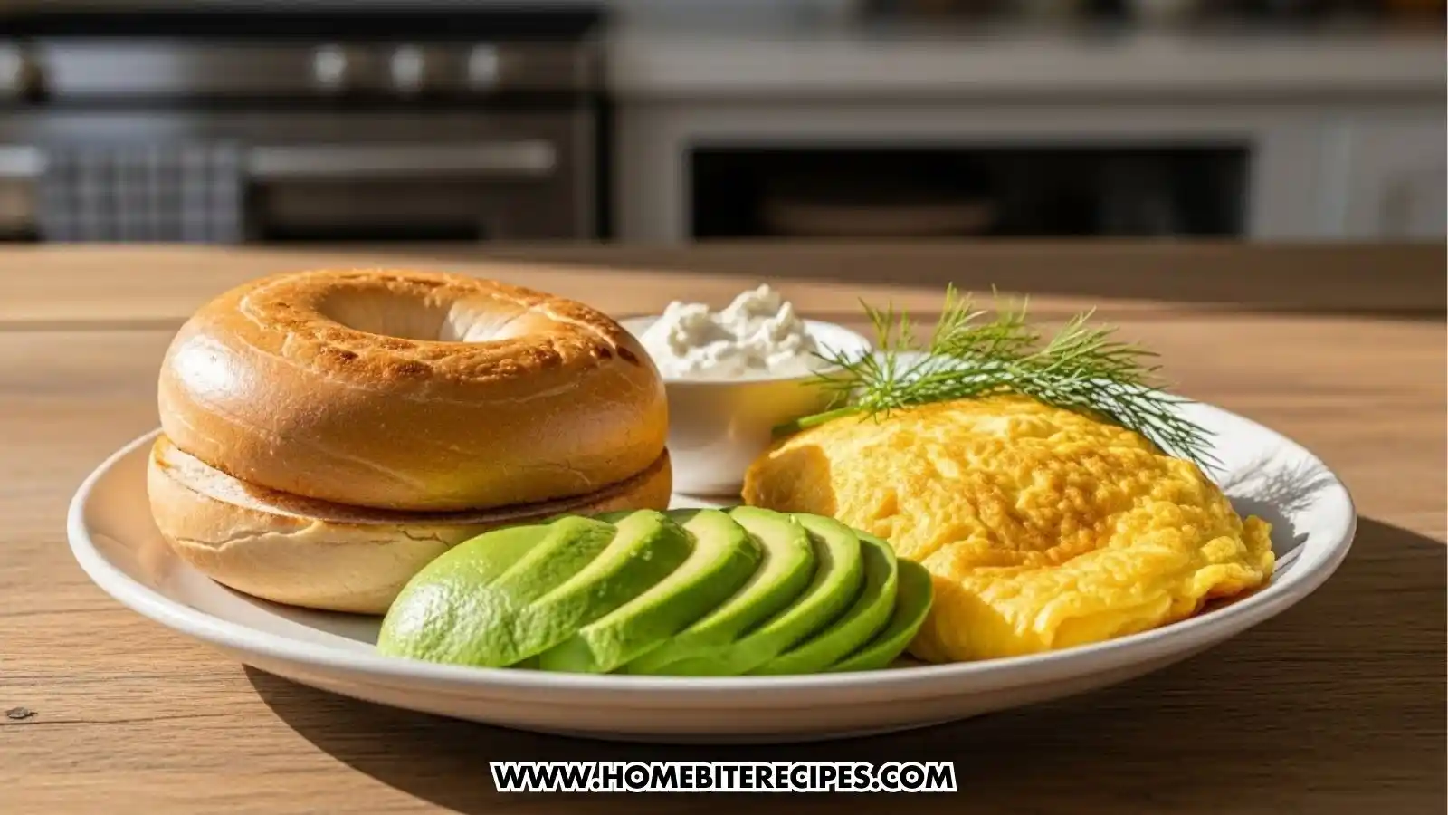 A plated meal featuring a toasted, plain bagel sliced in half next to a folded yellow omelet garnished with fresh dill. Several slices of bright green avocado are arranged in a fan shape in the foreground, with a small ramekin of white dip in the center.