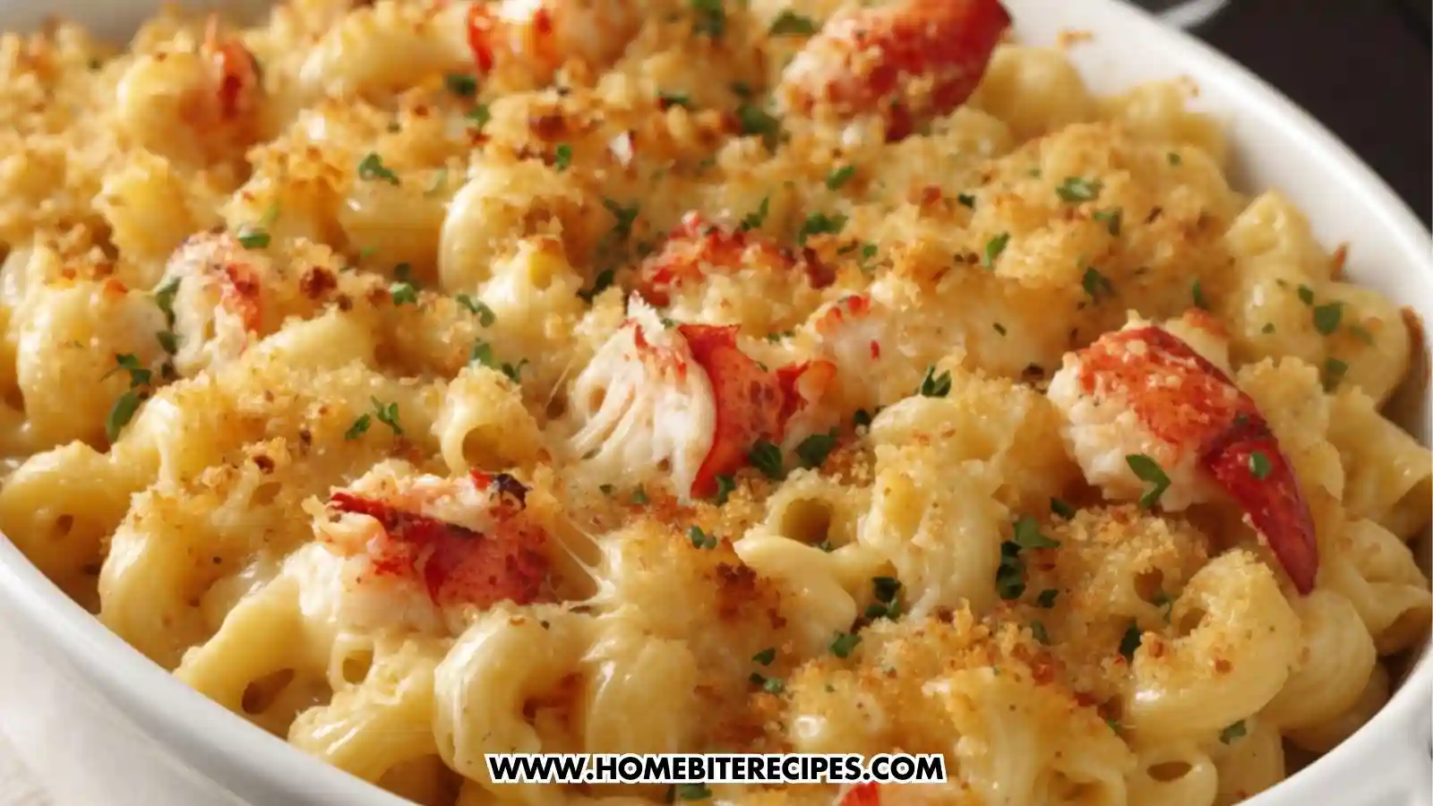 Close-up of creamy lobster mac and cheese in a white baking dish, topped with golden crispy breadcrumbs, fresh parsley, and stretchy melted cheese.