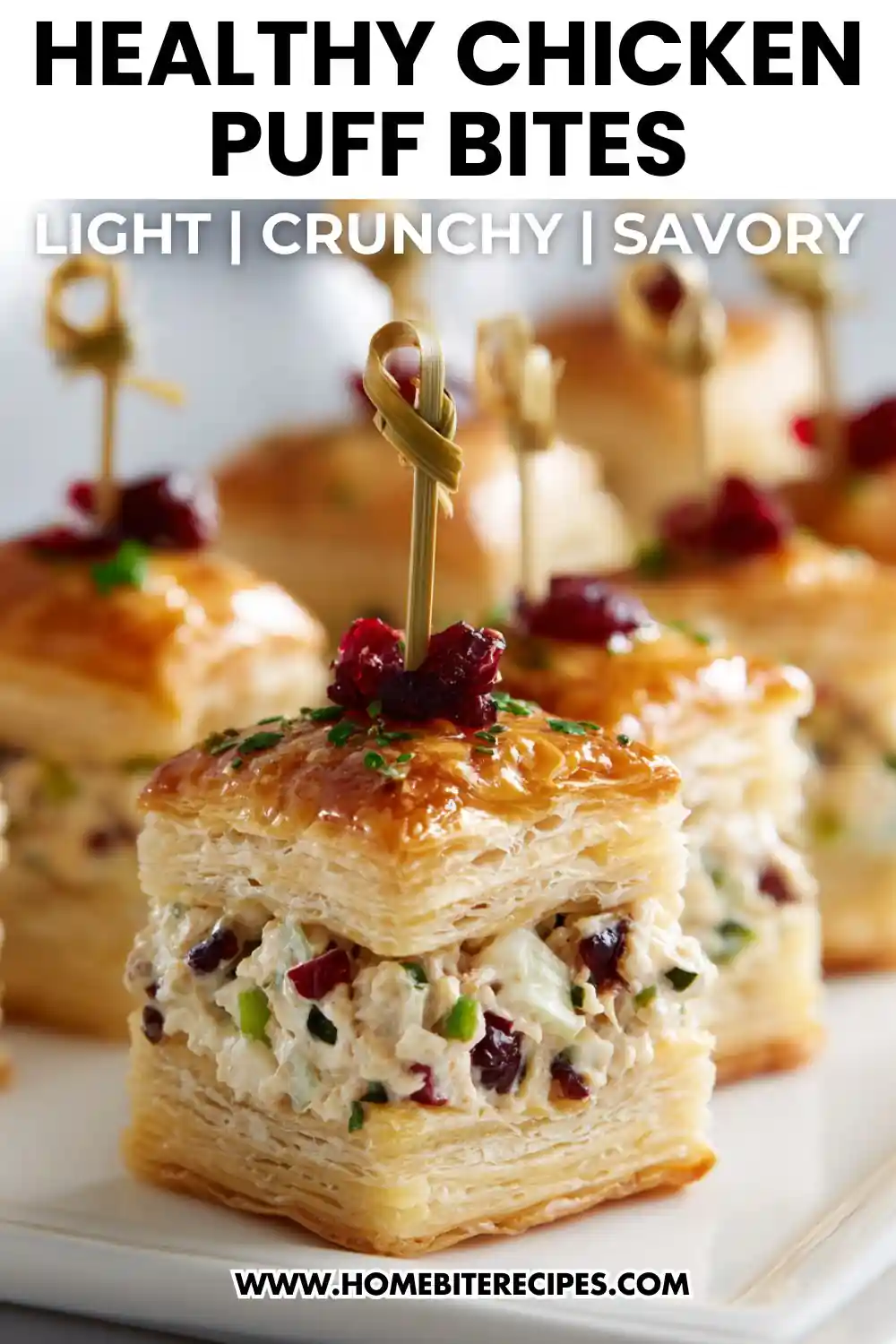 Close-up of healthy chicken puff pastry bites filled with creamy chicken salad, topped with herbs and cranberries, served as a bite-sized party appetizer