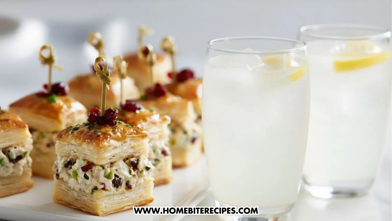 Close-up of healthy chicken puff pastry bites filled with creamy chicken salad, topped with herbs and cranberries, served as a bite-sized party appetizer