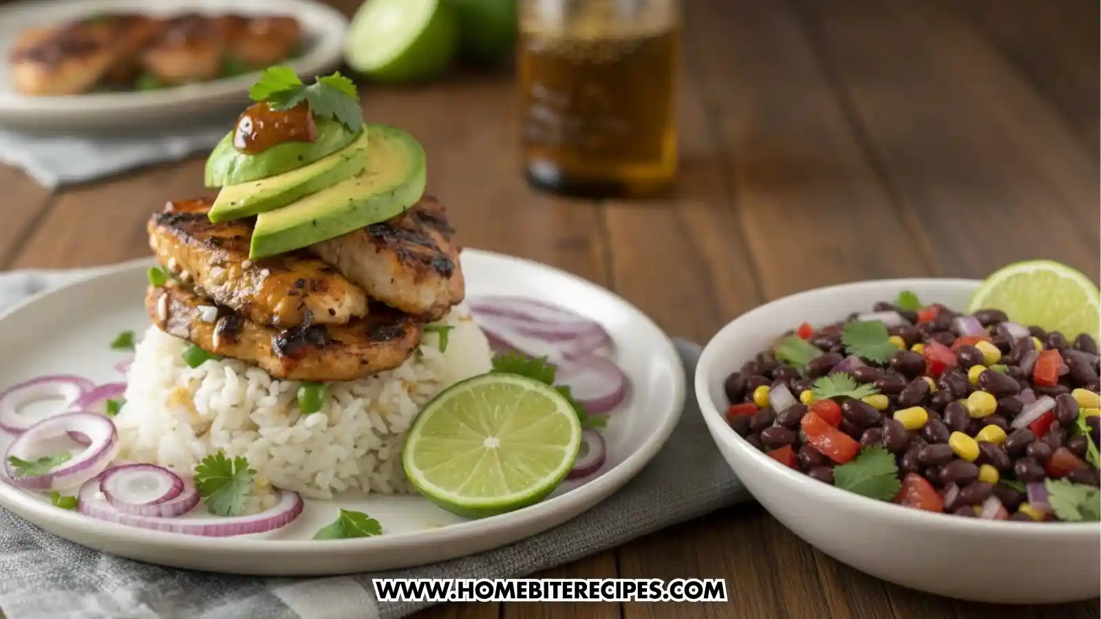 A finished meal featuring grilled cilantro lime chicken strips stacked on a bed of white rice, topped with fresh avocado slices and a dollop of salsa. The plate is garnished with red onion rings, cilantro, and a lime wedge. A side bowl of black bean salad with corn and peppers is visible to the right.