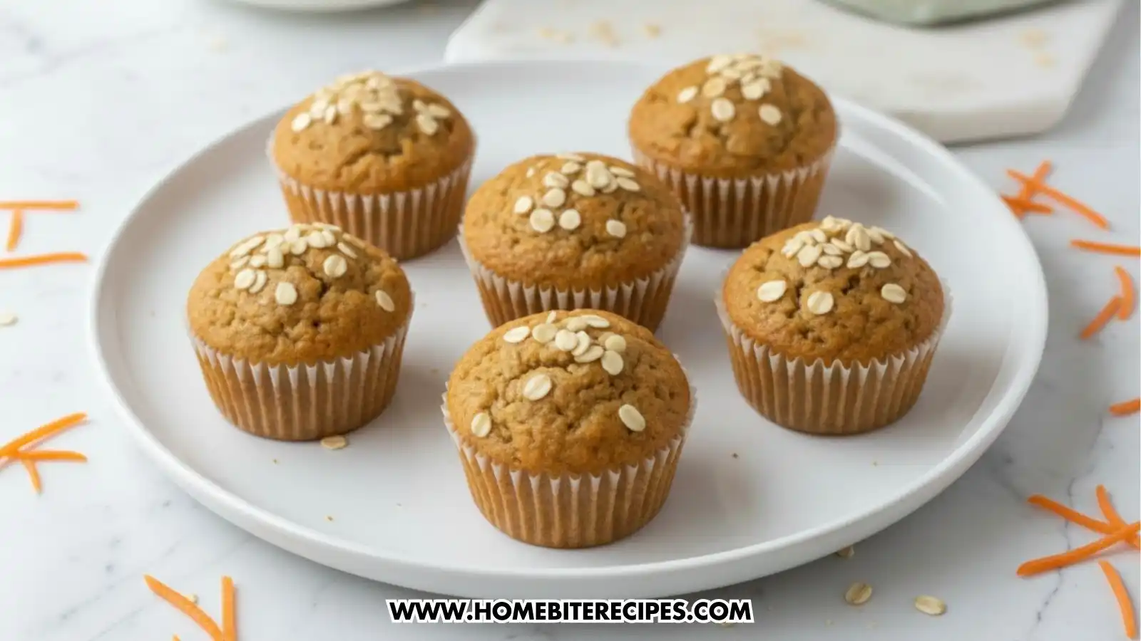 Close-up photo of freshly baked healthy carrot and oat muffins topped with oats, arranged on a white plate.
